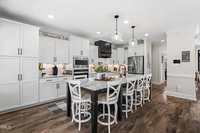 a kitchen with stainless steel appliances kitchen island granite countertop a table chairs and a refrigerator