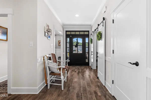 a view of a hallway with wooden floor and a bathroom