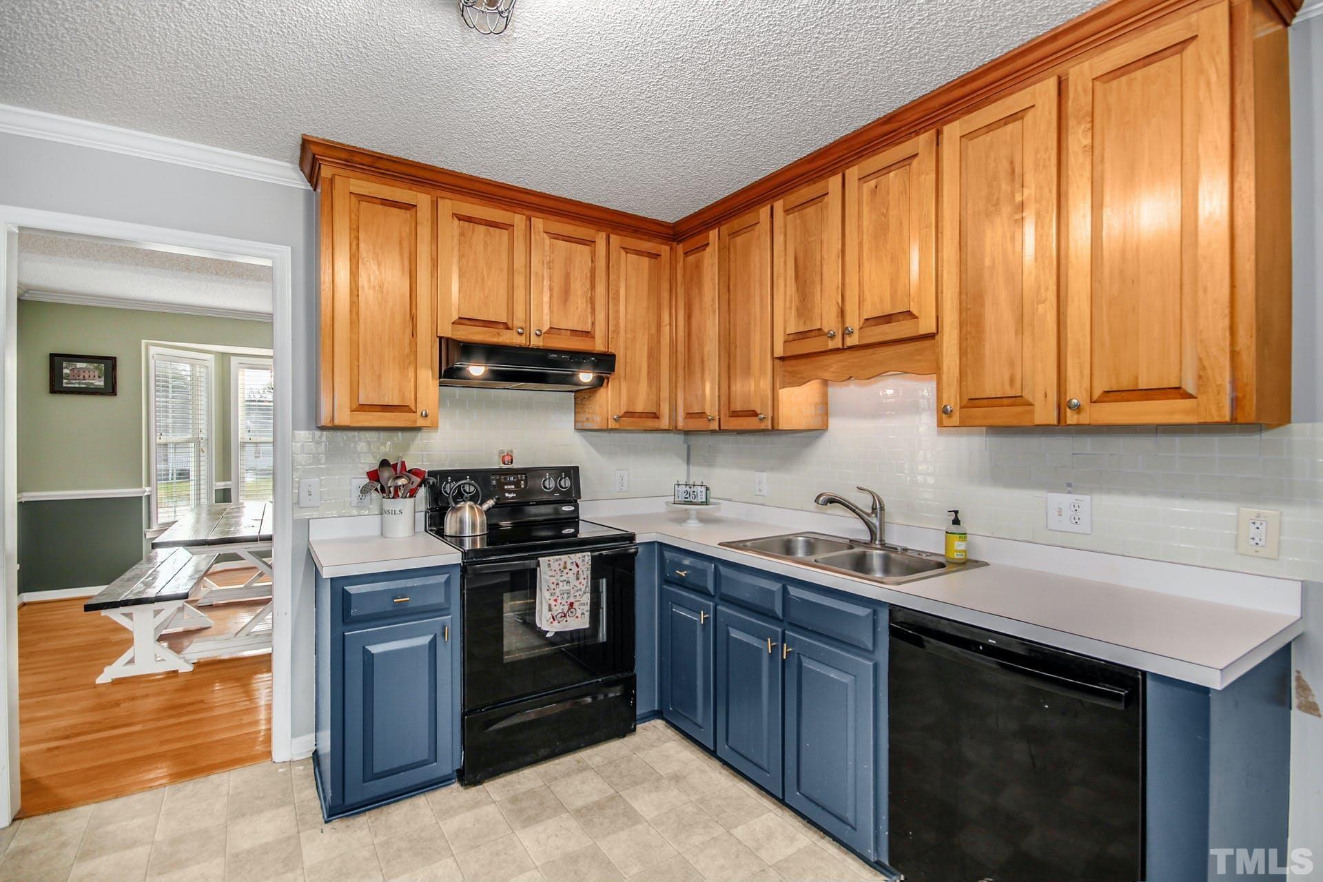 1013 Holland Ridge Drive Raleigh, NC 27603 - Photo 9 of 29 a kitchen with stainless steel appliances granite countertop wooden cabinets a sink and dishwasher a stove top oven with wooden floor