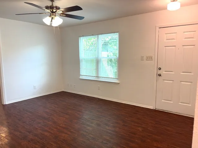 a view of an empty room with wooden floor and a window