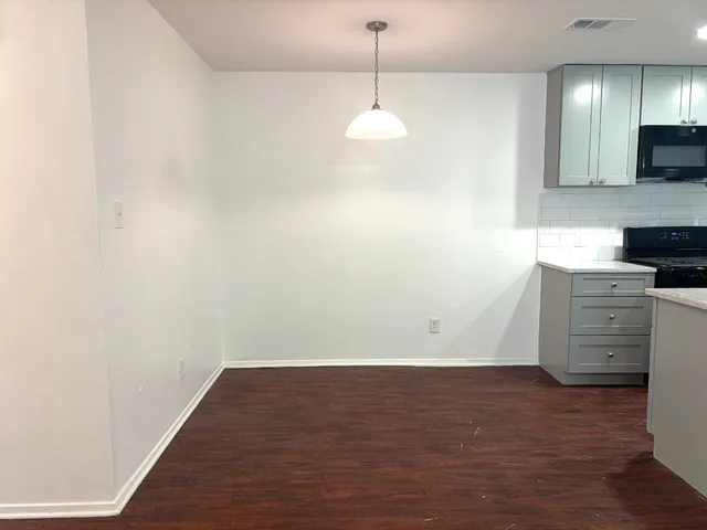 a view of a kitchen with an empty space and wooden floor