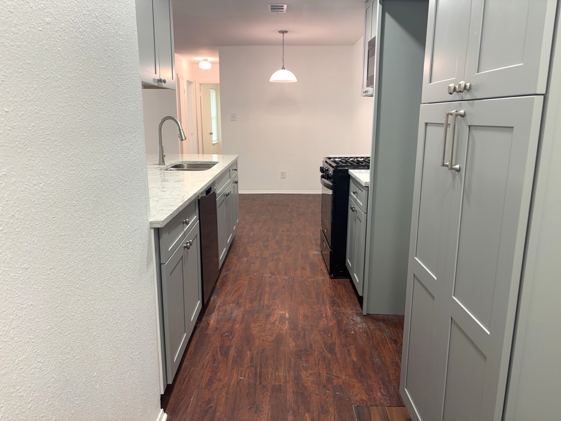16005 Stoneham Circle Pflugerville, TX 78660 - Photo 7 of 18 Kitchen with black gas range oven, gray cabinets, dark wood-style floors, stainless steel dishwasher, and light stone countertops