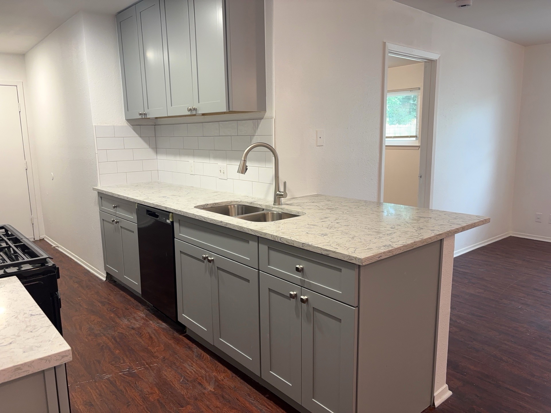 16005 Stoneham Circle Pflugerville, TX 78660 - Photo 9 of 18 Kitchen featuring gray cabinets, black appliances, dark wood-type flooring, decorative backsplash, and light stone countertops