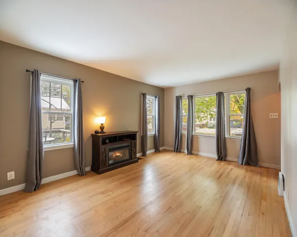 an empty room with windows a fireplace and wooden floor