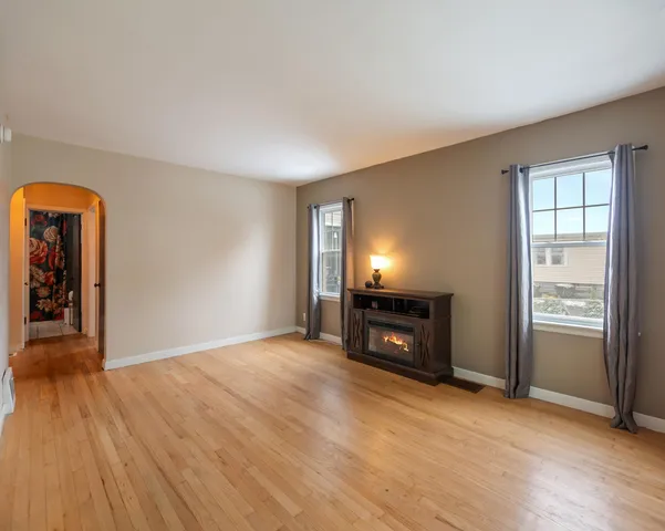 an empty room with windows fireplace and wooden floor