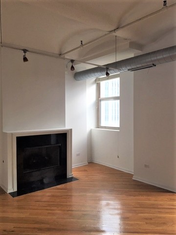 500 South Clinton Street, Unit 611 Chicago, IL 60607 - Photo 10 of 19 a view of empty room with wooden floor and fireplace