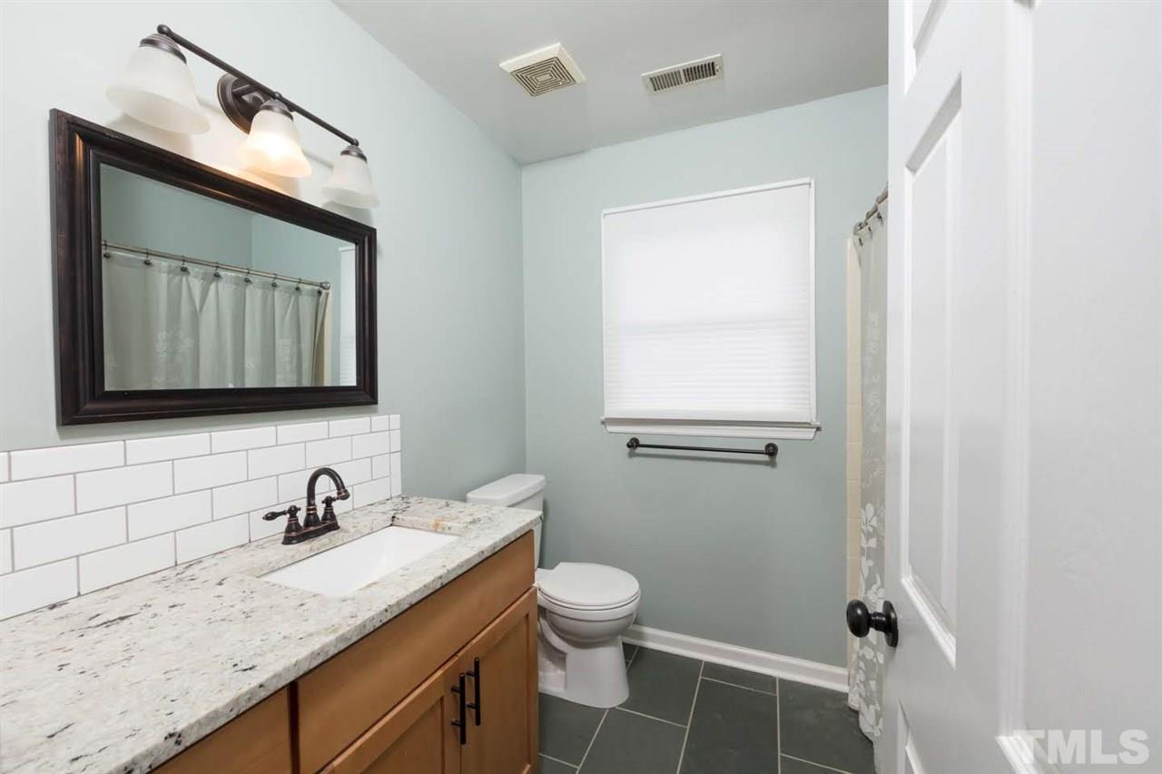 4713 Tolley Court Raleigh, NC 27616 - Photo 24 of 28 a bathroom with a granite countertop sink toilet a mirror and vanity