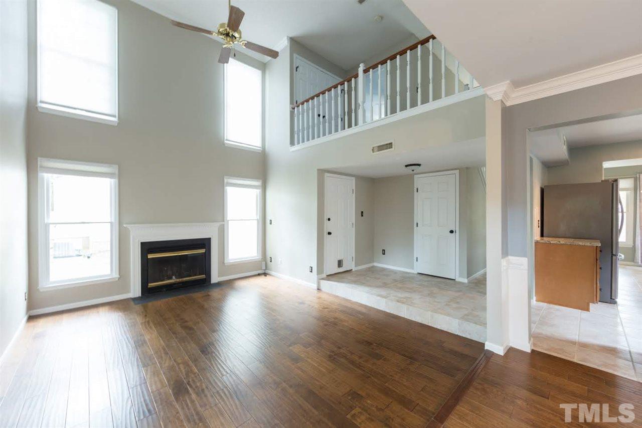 4713 Tolley Court Raleigh, NC 27616 - Photo 5 of 28 an empty room with windows fireplace and wooden floor