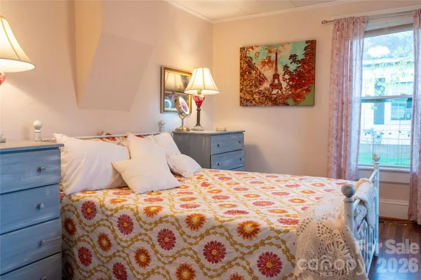 a bedroom with a bed and a lamp on dresser