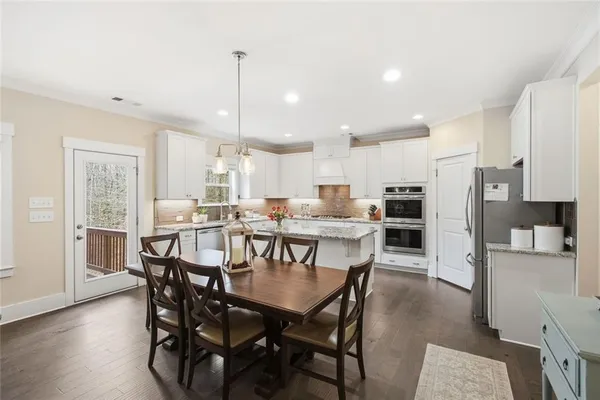 a kitchen with stainless steel appliances granite countertop a stove top oven a sink a refrigerator and white cabinets