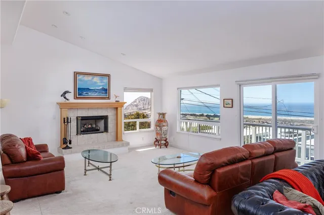 a living room with furniture a fireplace and large windows