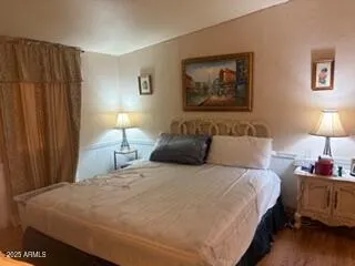 a bedroom with bed and wall painting with wooden floor