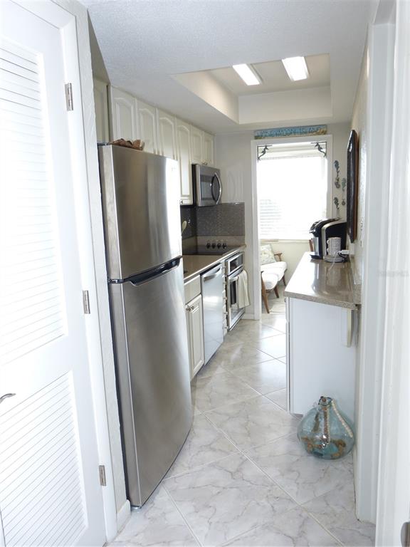 2 Causeway Boulevard, Unit 206 Dunedin, FL 34698 - Photo 11 of 26 a kitchen with granite countertop stainless steel appliances a refrigerator a stove a sink and a refrigerator