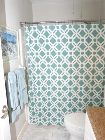 a bathroom with a granite countertop sink and a toilet