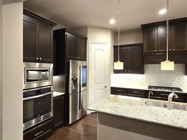a kitchen with granite countertop stainless steel appliances and refrigerator