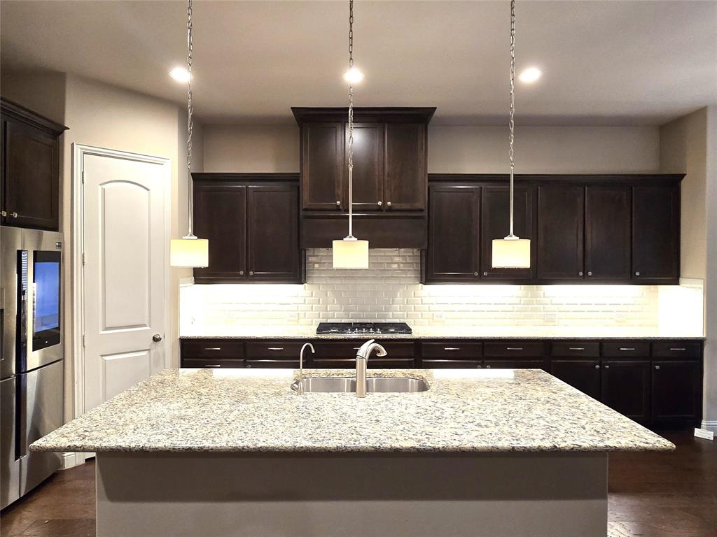 680 Wingate Road Coppell, TX 75019 - Photo 10 of 23 a kitchen with kitchen island granite countertop a refrigerator and a sink