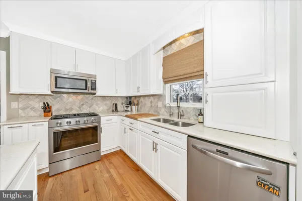 a kitchen with granite countertop white cabinets stainless steel appliances and a sink