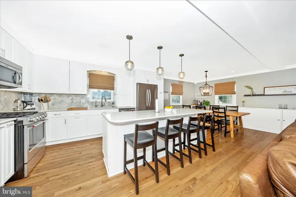 a kitchen with stainless steel appliances kitchen island granite countertop a table chairs sink and cabinets