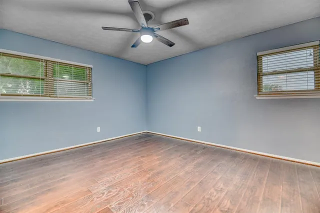 an empty room with a ceiling fan and window