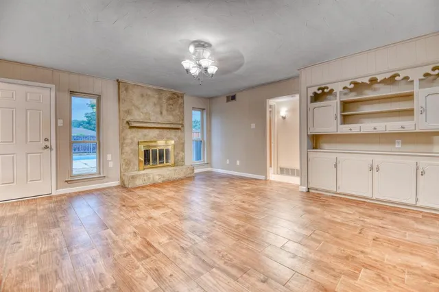 a view of an empty room with kitchen and a window