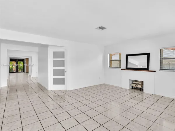 a view of an empty room with window and a kitchen