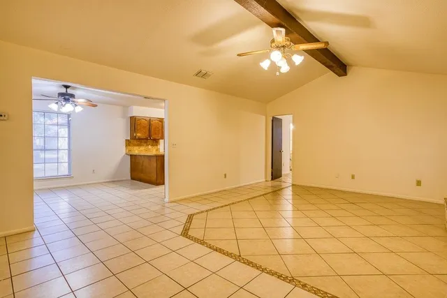 a view of an empty room and chandelier fan