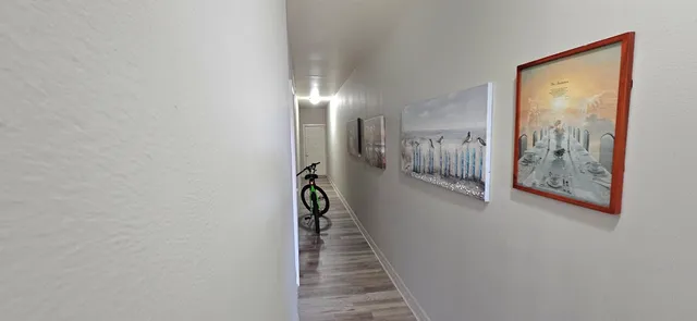 a view of a hallway with wooden floor and closet
