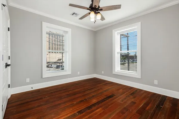 a view of an empty room with wooden floor and a window
