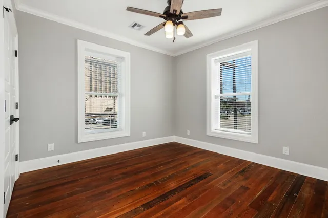 a view of an empty room with wooden floor and a window