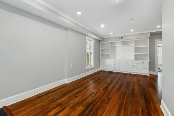 a view of empty room with wooden floor and windows