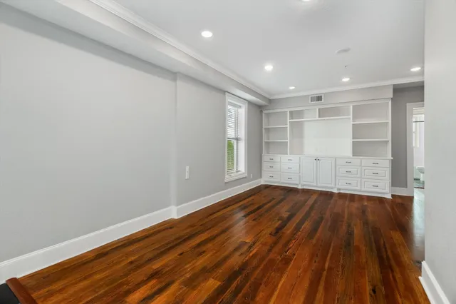 a view of empty room with wooden floor and windows