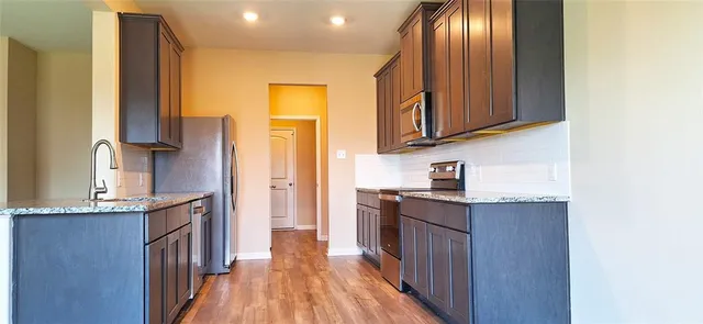a kitchen with granite countertop a sink a stove cabinets and wooden floor