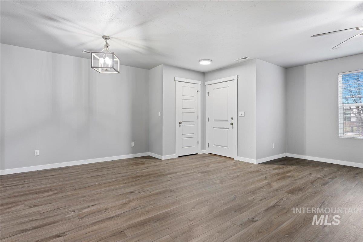 2513 East Goldstone Street Meridian, ID 83642 - Photo 6 of 27 Empty room featuring wood finished floors, a ceiling fan, and hanging lights