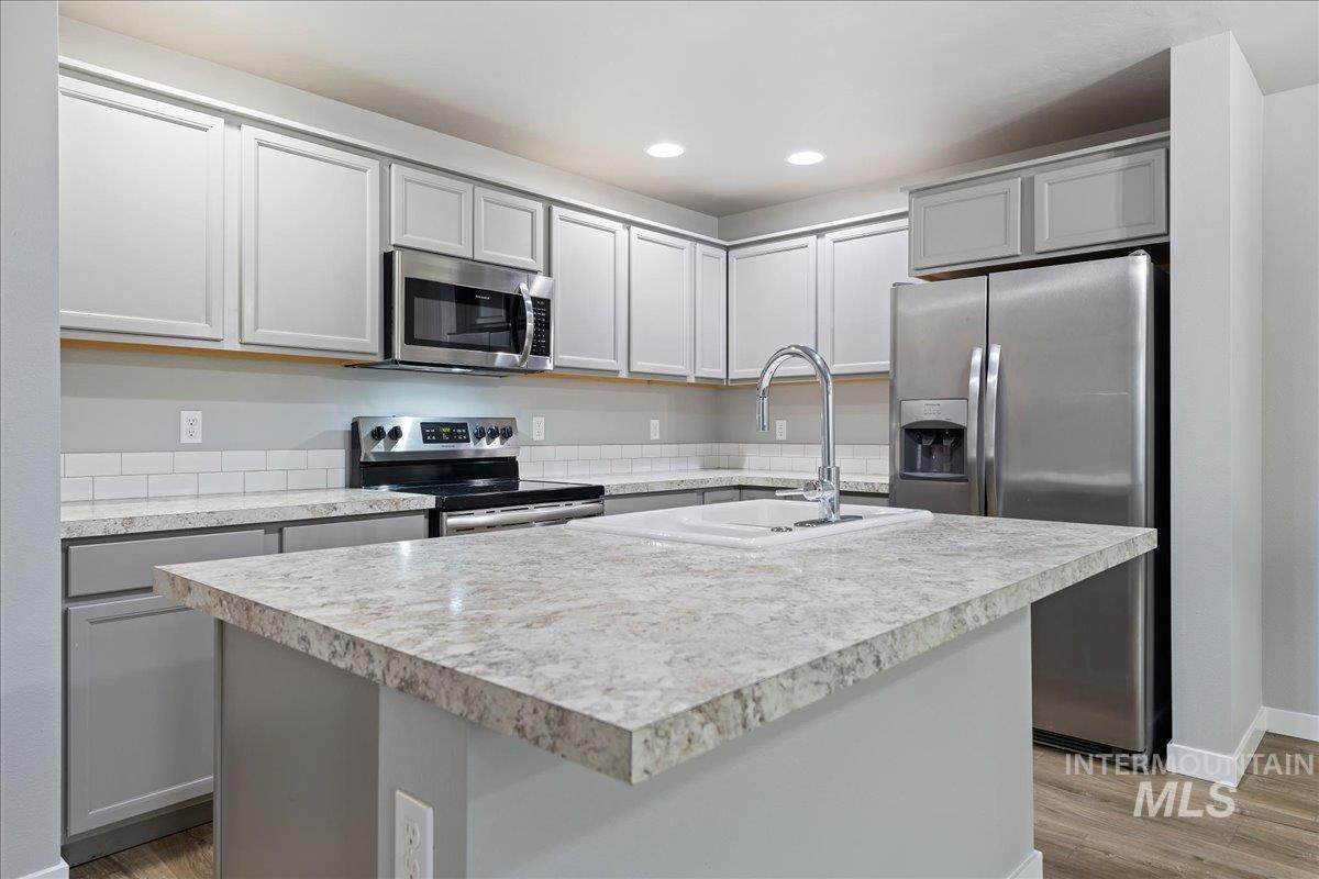 2513 East Goldstone Street Meridian, ID 83642 - Photo 7 of 27 Kitchen featuring light countertops, gray cabinetry, stainless steel appliances, an island with sink, and recessed lighting