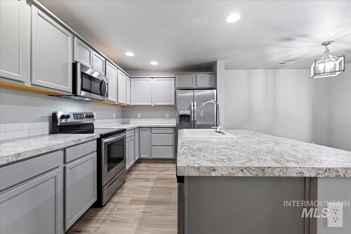 2513 East Goldstone Street Meridian, ID 83642 - Photo 8 of 27 Kitchen with gray cabinets, stainless steel appliances, and light countertops