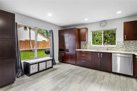 a kitchen with wooden floors a sink a window and appliances