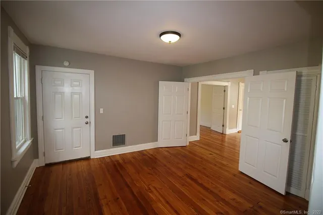 a view of an empty room with wooden floor and a bathroom