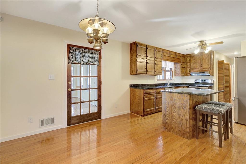 10185 Henry Mill Road Chattahoochee Hills, GA 30213 - Photo 16 of 41 a kitchen with stainless steel appliances granite countertop a stove top oven a sink dishwasher and white cabinets with wooden floor
