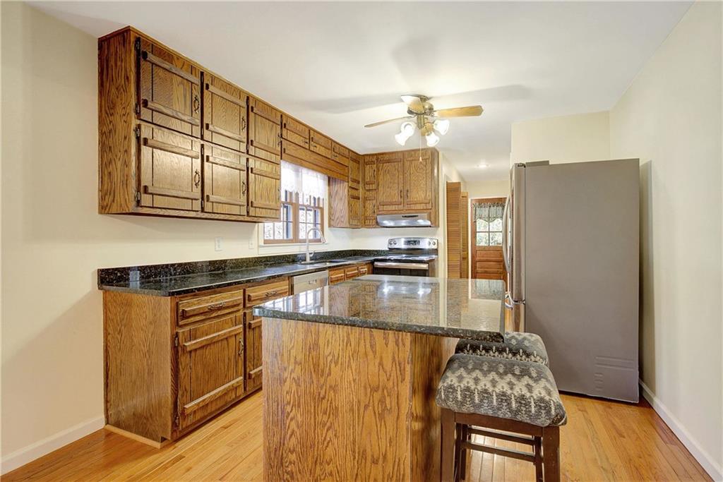 10185 Henry Mill Road Chattahoochee Hills, GA 30213 - Photo 20 of 41 a kitchen with granite countertop a stove a sink dishwasher and white cabinets with wooden floor