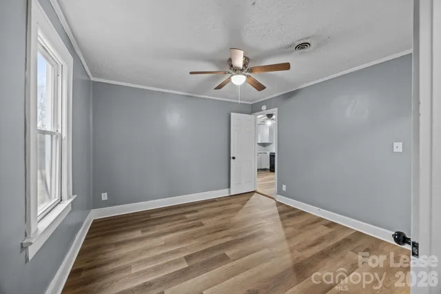a view of empty room with wooden floor and fan