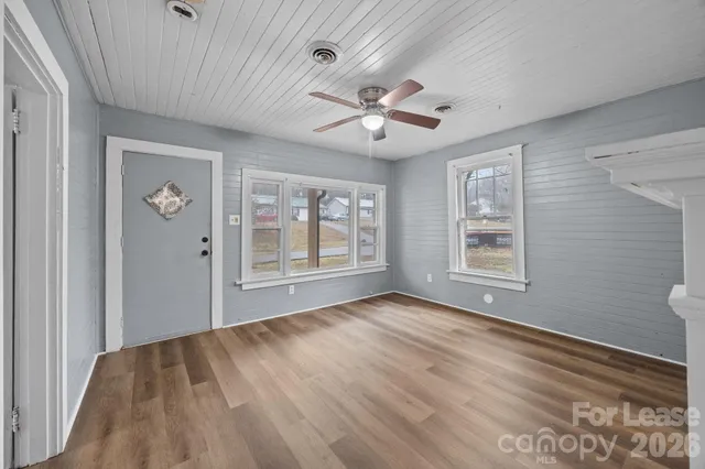 a view of an empty room with a window and wooden floor