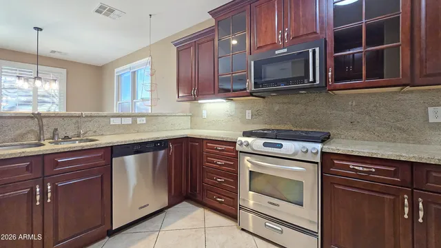 a kitchen with granite countertop a stove microwave oven a sink and dishwasher with wooden cabinets