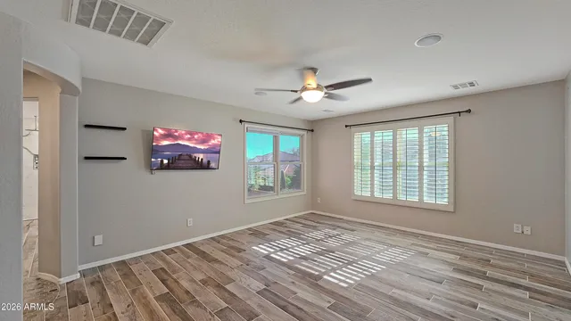 a view of an empty room with a window and wooden floor