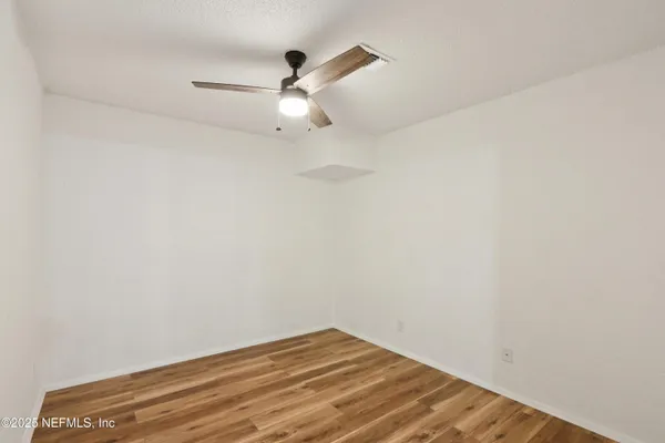 an empty room with a window and a fan