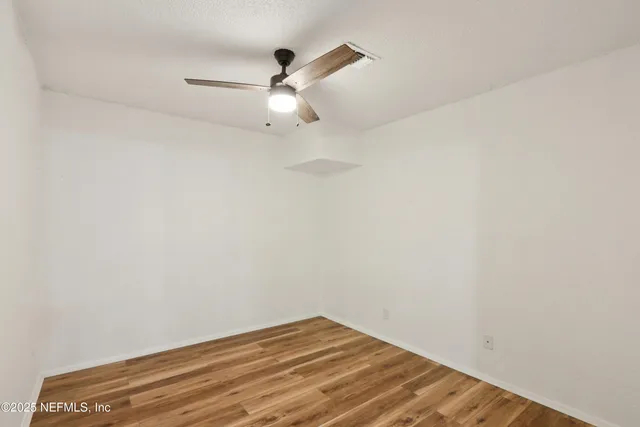 an empty room with a window and a fan