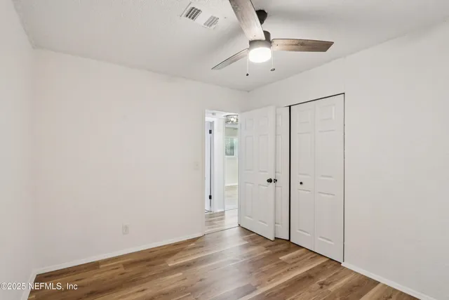an empty room with wooden floor and a ceiling fan
