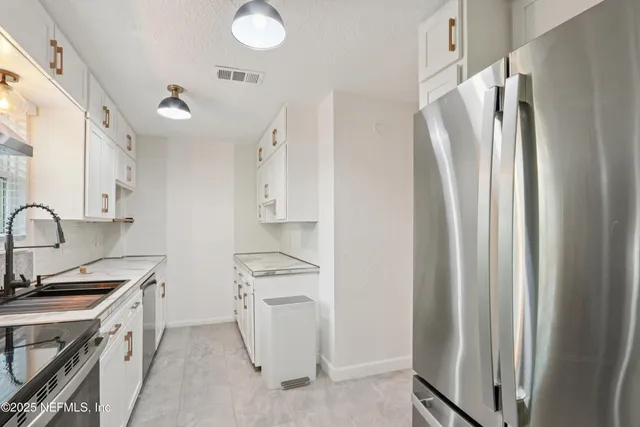 a kitchen with stainless steel appliances a refrigerator sink and white cabinets