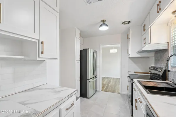 a kitchen with granite countertop a refrigerator stove and sink