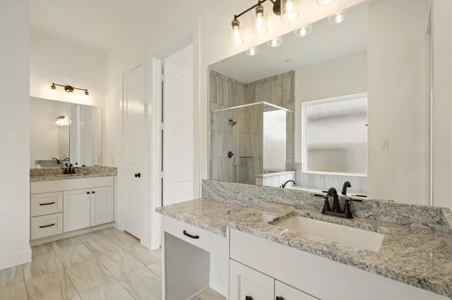 a bathroom with a granite countertop double vanity sink and mirror