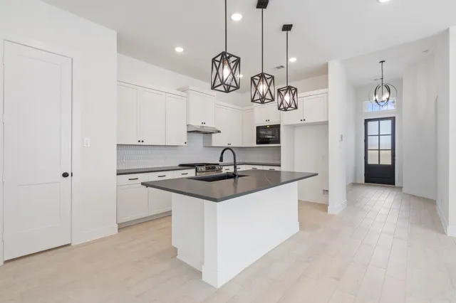 a kitchen with granite countertop a sink a stove and cabinets